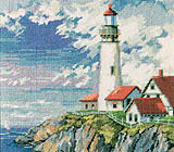 Fluffy white clouds and a deep blue sky set off a grouping of red-roofed buildings surrounding a towering lighthouse.